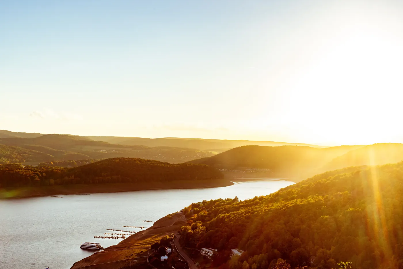 Luftaufnahme eines Flusstals mit bewaldeten Hängen im goldenen Abendlicht